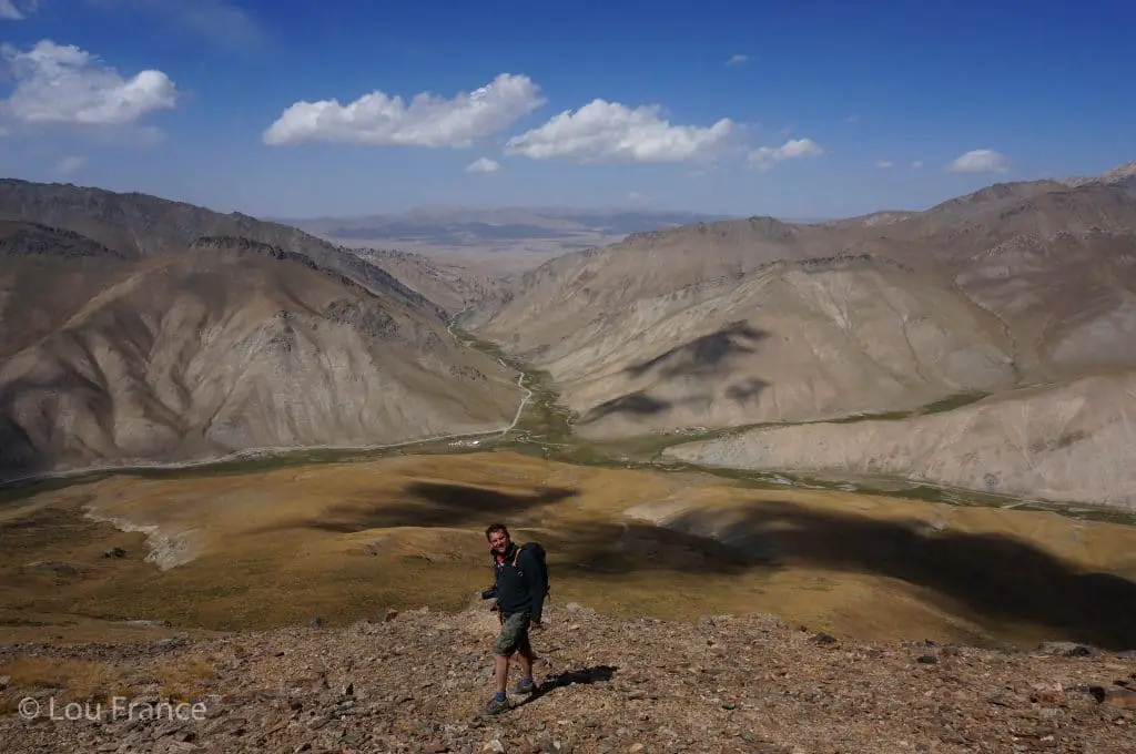 A man hiking amongst arid mountains. Hiking is on of the best things to when backpacking Kyrgyzstan