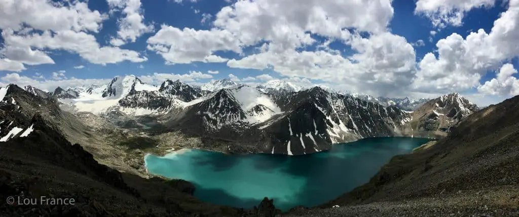 Beautiful aqua blue alpine lake with snow capped mountains. Ala Kul lake hike is popular backpackers in Kyrgyzstan